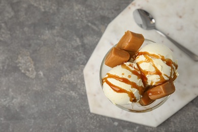 Photo of Delicious ice cream with caramel and sauce served on table, top view. Space for text