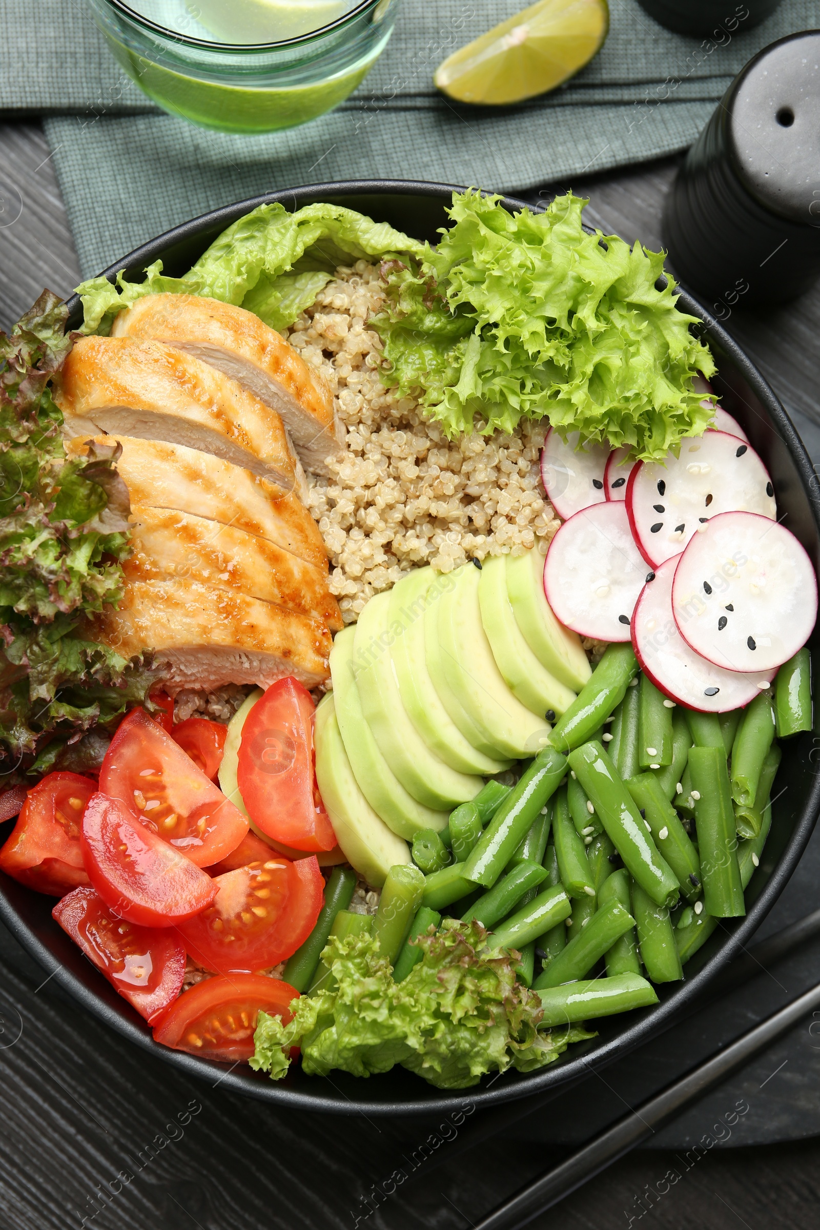 Photo of Healthy meal. Tasty products in bowl on black wooden table, top view