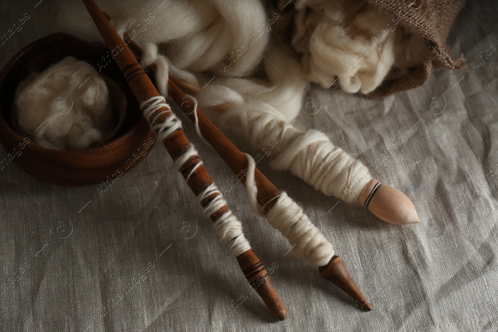 Photo of Soft white wool and spindles on table