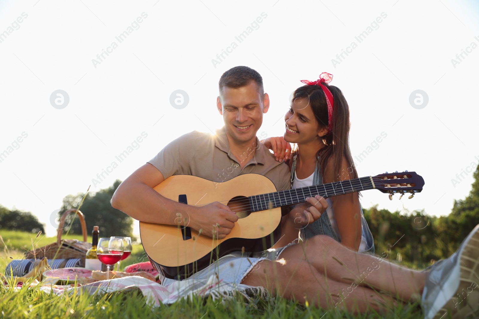 Photo of Happy couple with guitar on picnic in park