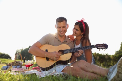 Happy couple with guitar on picnic in park