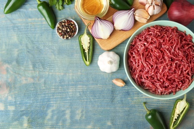 Flat lay composition with fresh raw minced meat on blue wooden table. Space for text