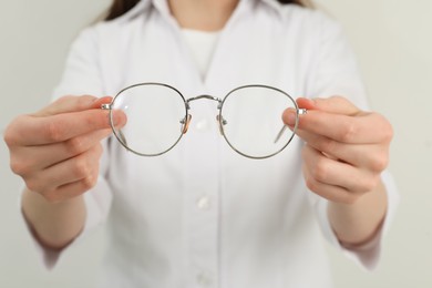 Woman with glasses on light background, closeup