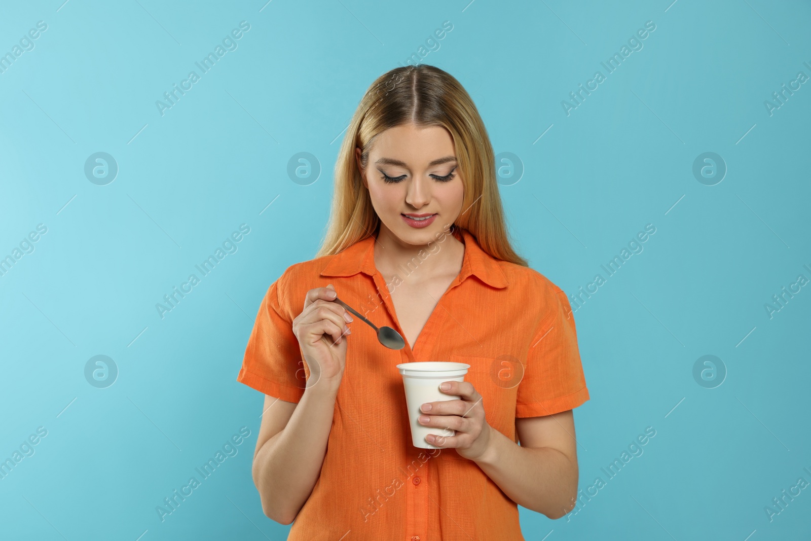 Photo of Woman with tasty yogurt on light blue background