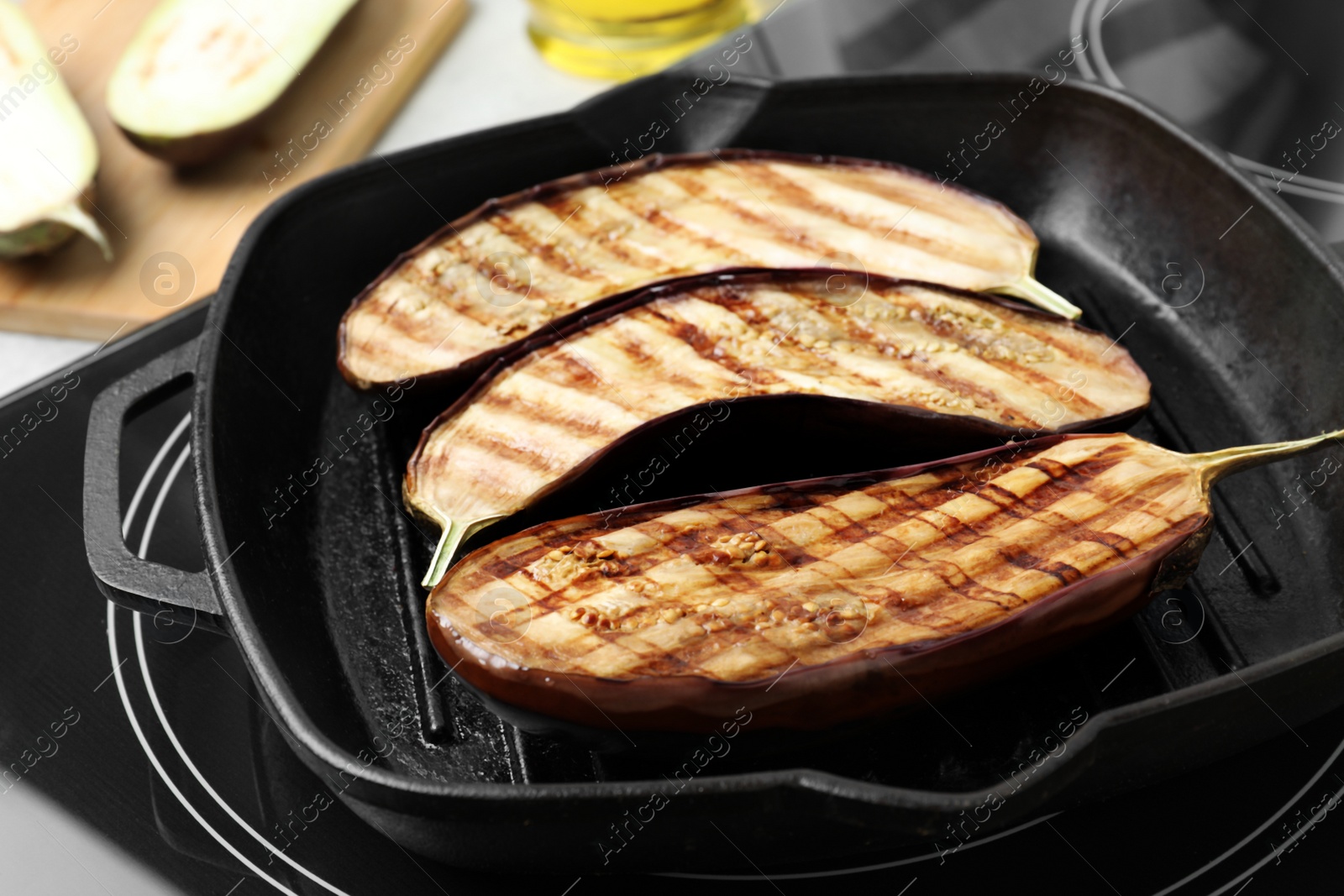 Photo of Delicious grilled eggplant halves in pan on stove, closeup