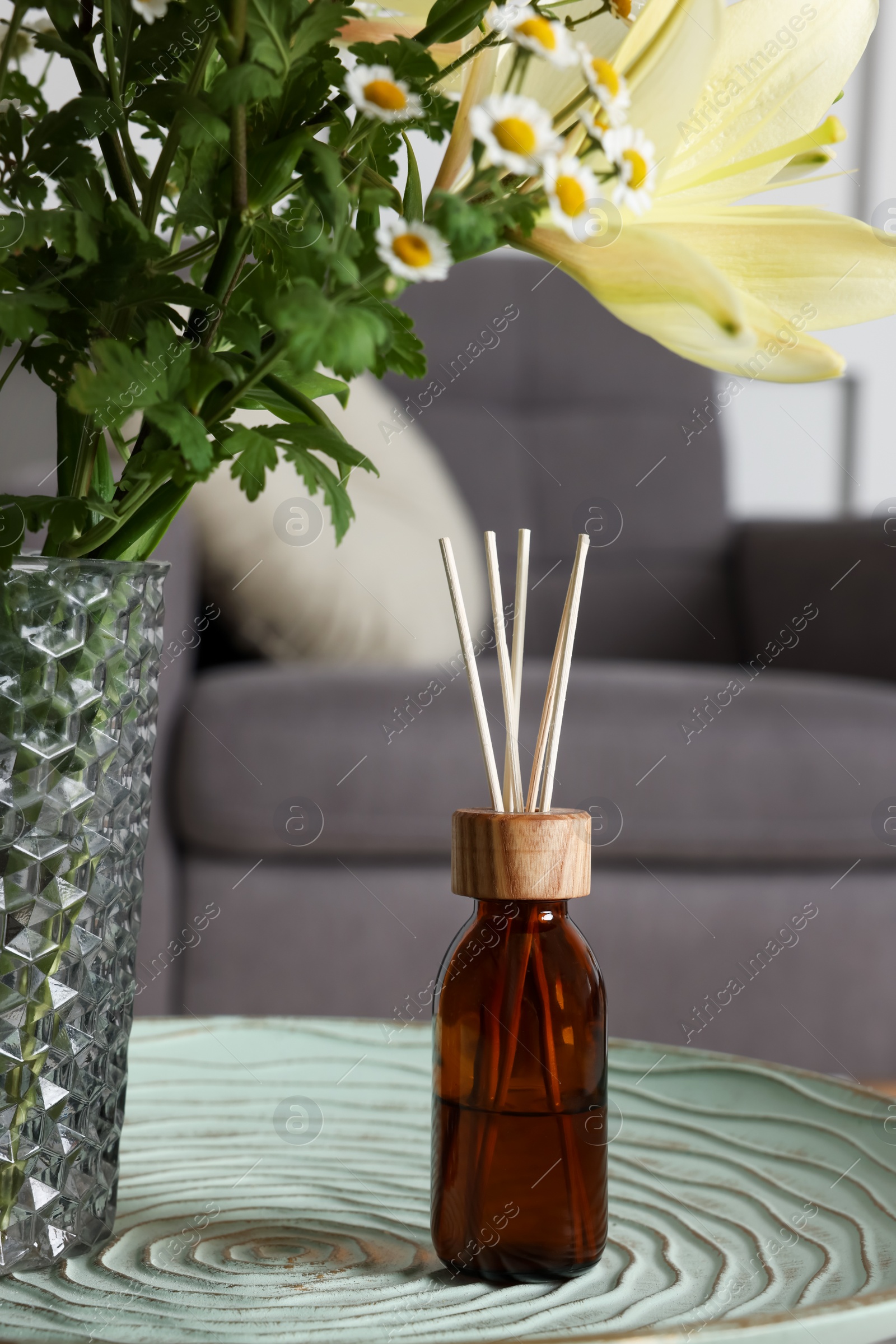 Photo of Aromatic reed air freshener near flowers on texture table