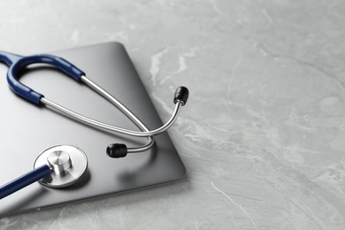 Modern laptop and stethoscope on grey table. Space for text