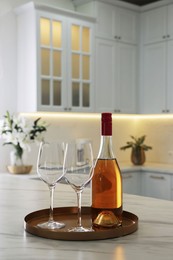 Photo of Bottle and glasses on white marble table in kitchen. Luxury interior