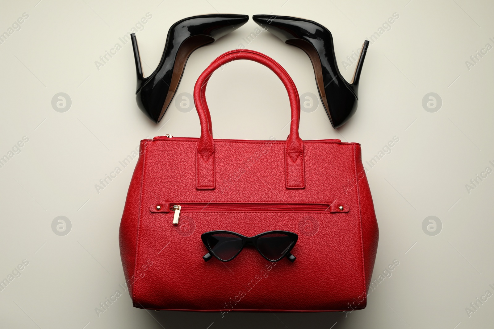 Photo of Stylish woman's bag, sunglasses and shoes on light background, flat lay