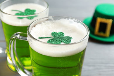 Photo of Green beer and clover leaves on table, closeup. St. Patrick's Day celebration