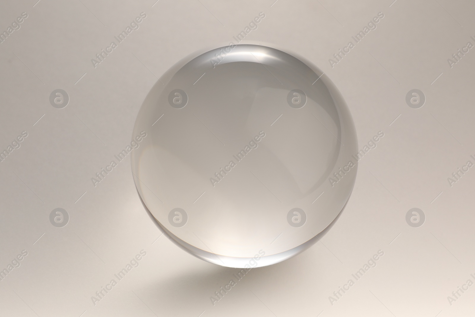 Photo of Transparent glass ball on light grey background