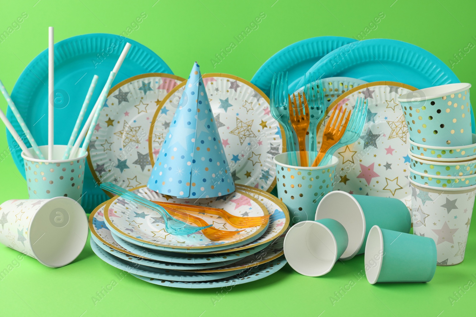 Photo of Set of disposable tableware on green background