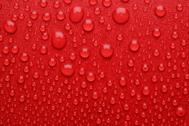 Water drops on red background, top view