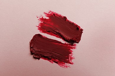 Photo of Smears of bright lipstick on light background, top view