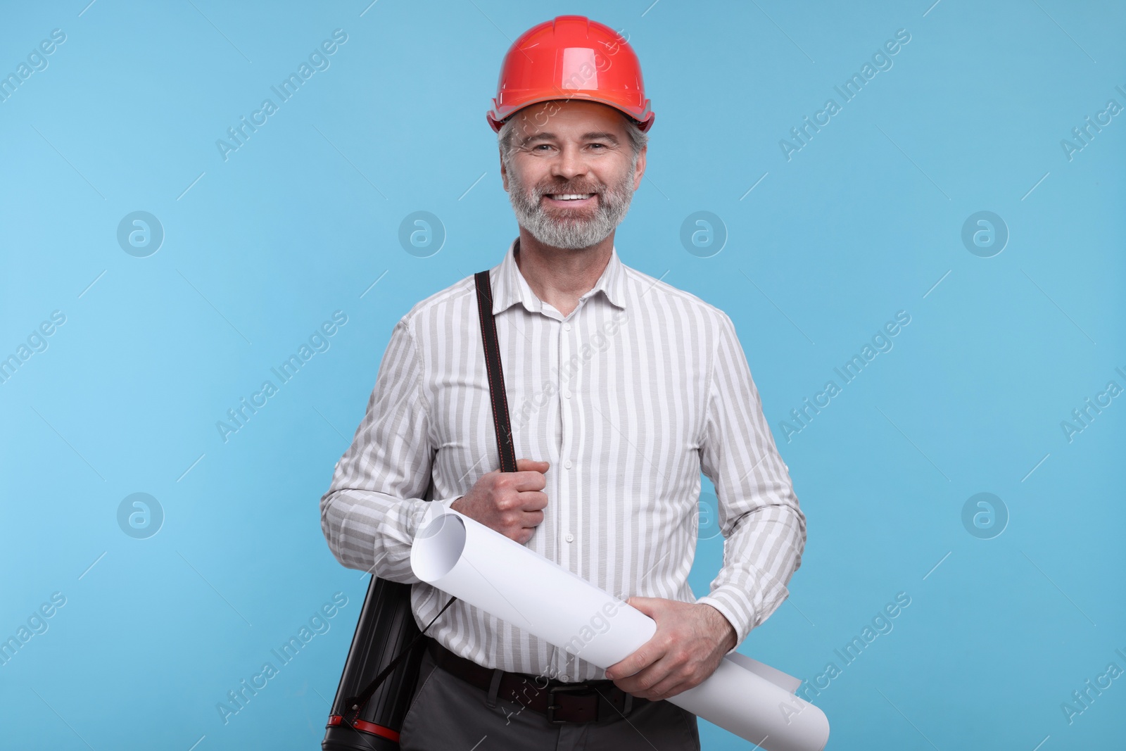 Photo of Architect in hard hat holding draft on light blue background