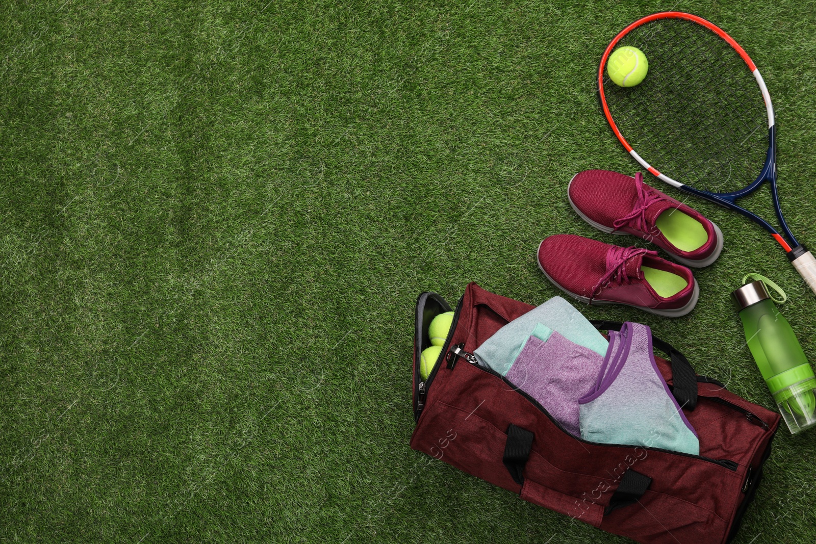 Photo of Gym bag and sports equipment on green grass, flat lay. Space for text