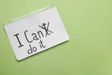 Photo of Motivation concept. Changing phrase from I Can't Do It into I Can Do It by crossing out letter T on light green background, top view. Space for text