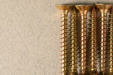 Photo of Many metal screws on beige background, flat lay. Space for text