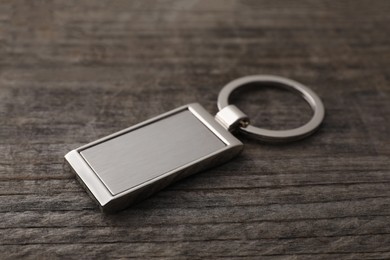 Photo of Metallic keychain on wooden background, closeup view