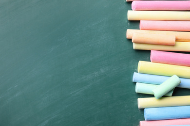 Photo of Pieces of color chalk on greenboard, flat lay. Space for text