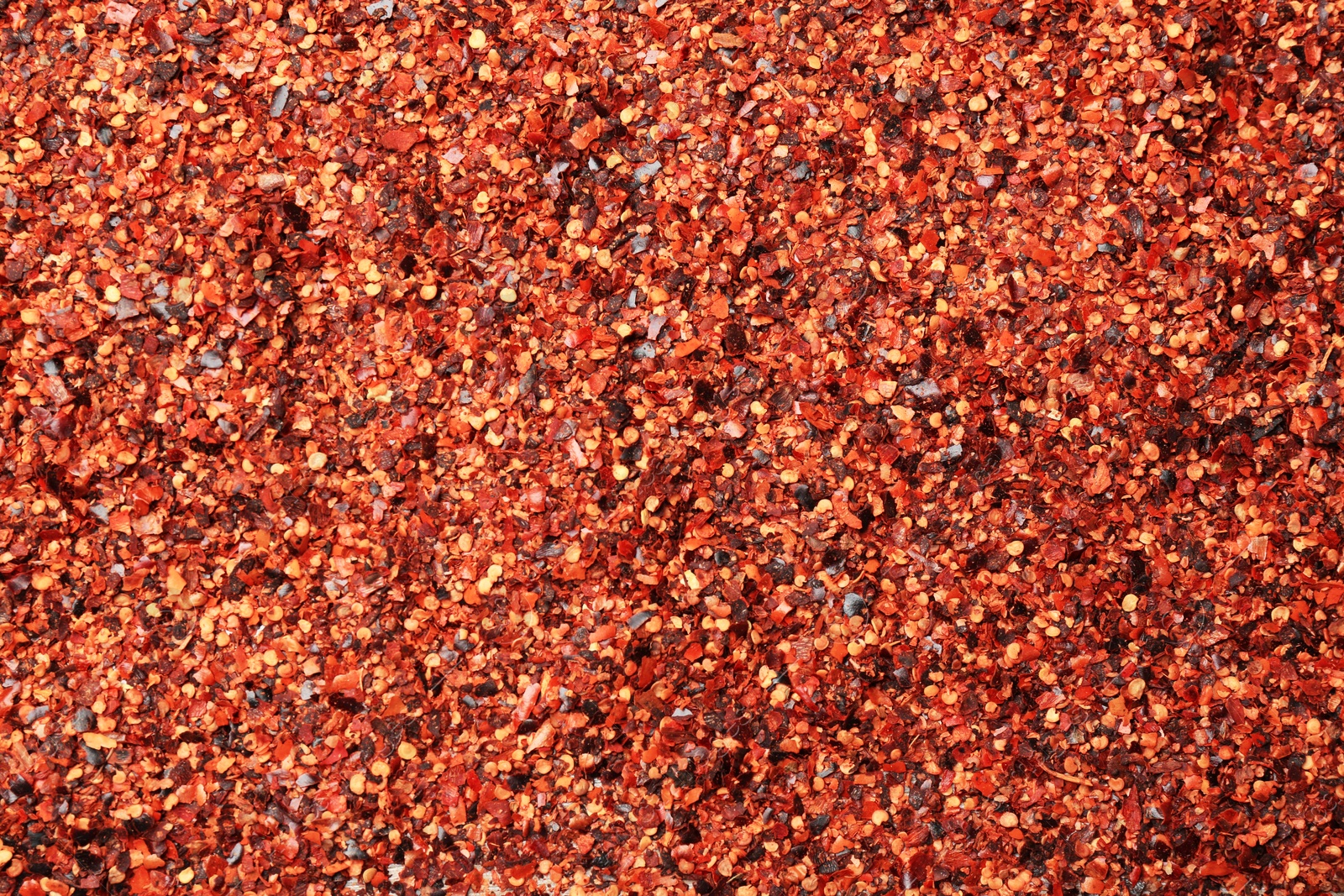 Photo of Chili pepper flakes as background, closeup