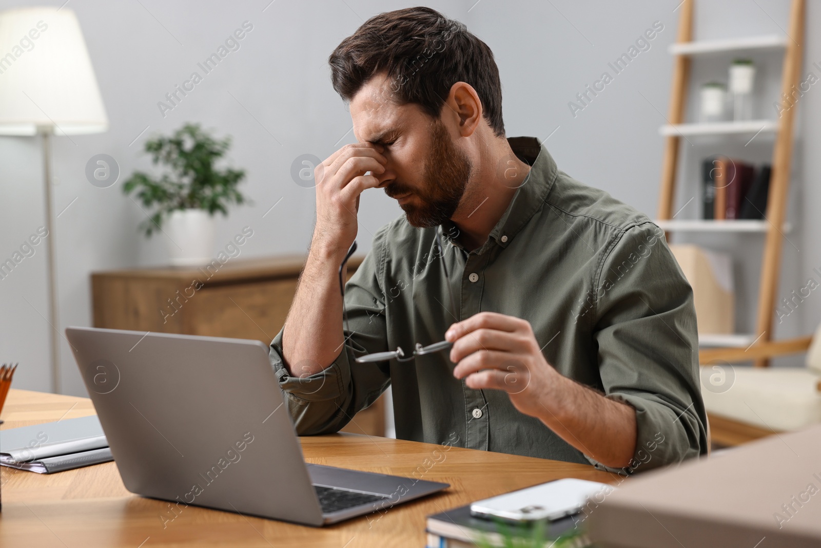 Photo of Tired man suffering from headache at workplace