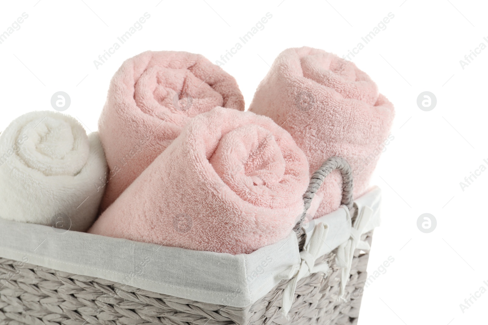 Photo of Rolled soft towels in basket on white background, closeup