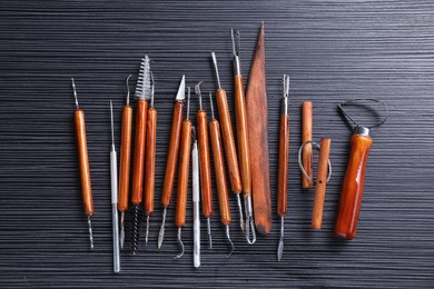 Photo of Set of clay crafting tools on black table, flat lay