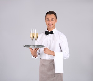 Photo of Waiter holding metal tray with glasses of champagne on grey background