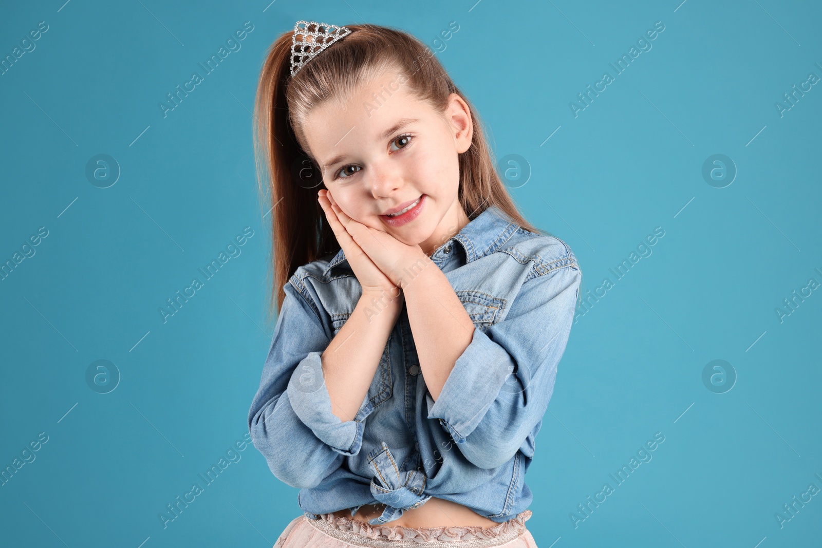 Photo of Cute girl in diadem on light blue background. Little princess