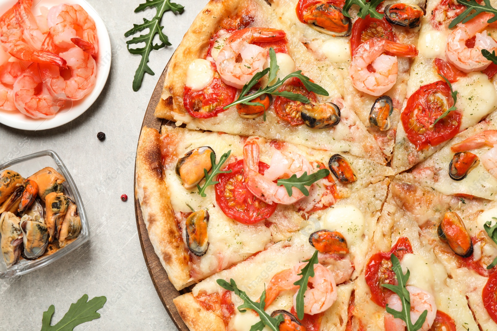 Photo of Delicious seafood pizza and fresh ingredients on light grey table, flat lay