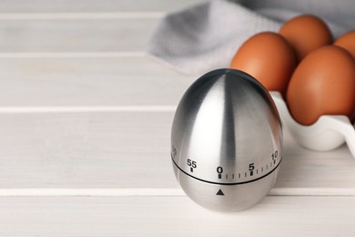 Photo of Kitchen timer and eggs on white wooden table. Space for text