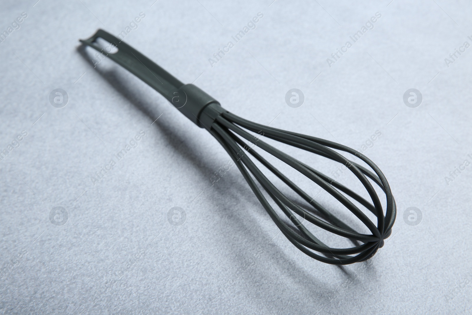 Photo of Plastic whisk on gray table, closeup. Kitchen tool