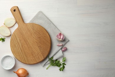 Photo of Cutting board, parsley, garlic and onion on white wooden table, flat lay. Space for text