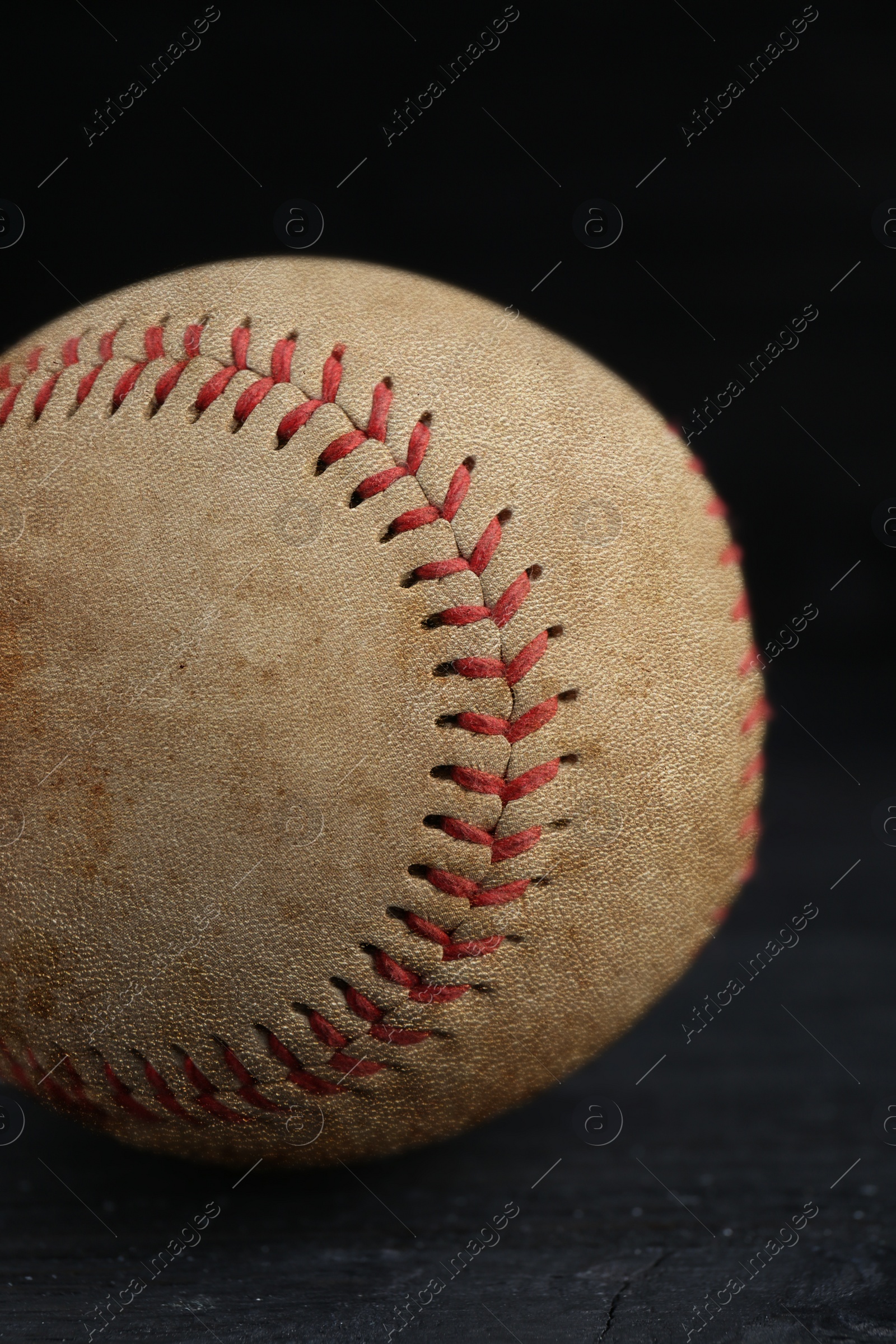 Image of Worn baseball ball on black background, closeup