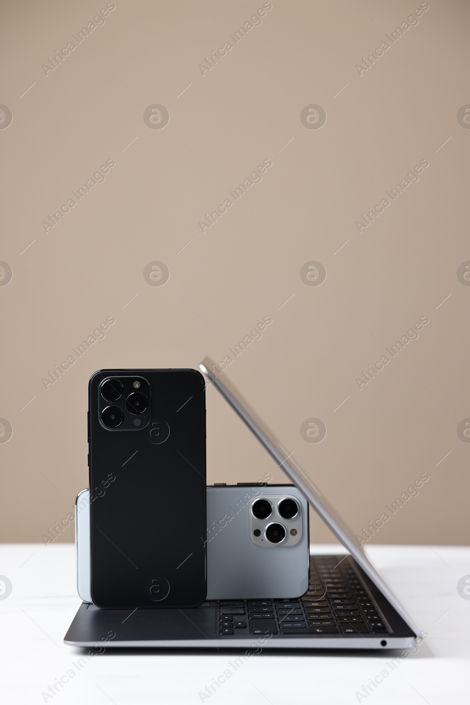 Photo of Modern laptop and smartphones on beige background