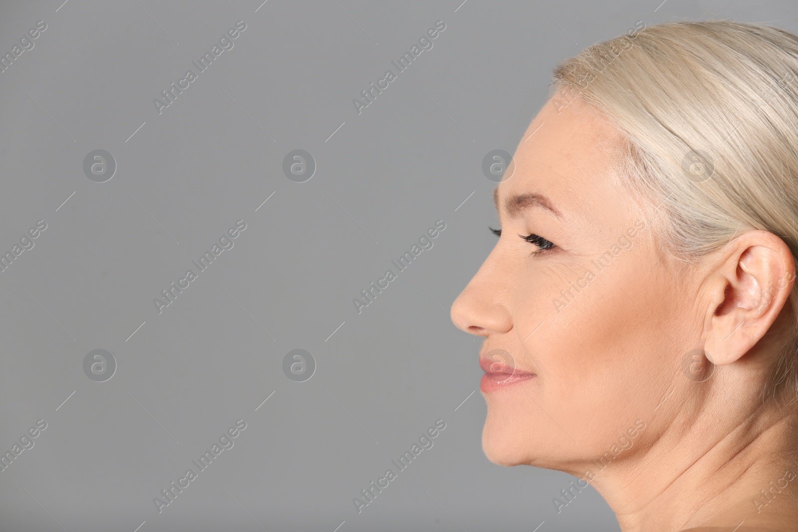 Photo of Portrait of beautiful mature woman on grey background, closeup. Space for text
