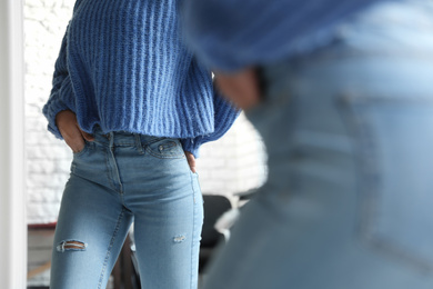 Woman wearing jeans near mirror indoors, closeup