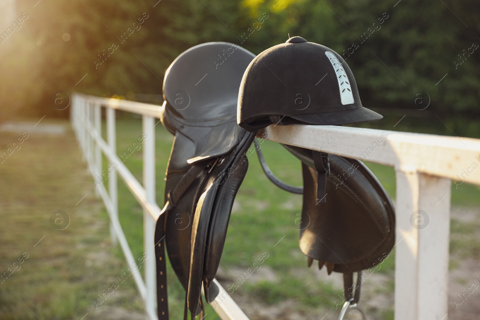 Photo of Leather horse saddle and helmet on wooden fence outdoors