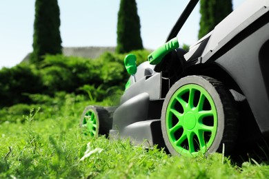 Photo of Lawn mower on green grass in garden, closeup. Space for text