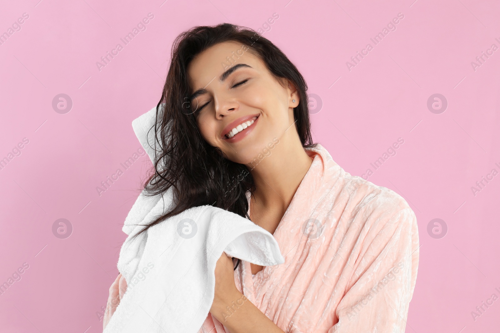 Photo of Young woman drying hair with towel on pink background