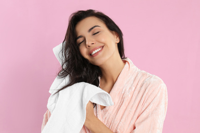 Young woman drying hair with towel on pink background