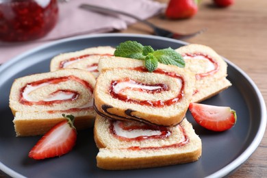 Photo of Tasty cake roll with strawberry jam and cream on plate, closeup