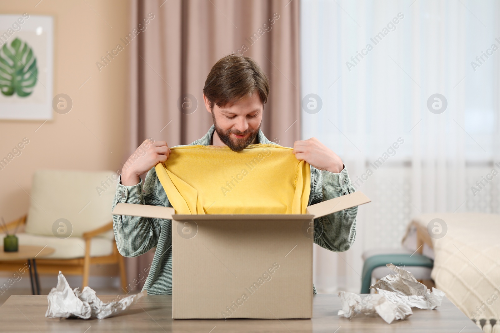 Photo of Happy man with parcel at home. Internet shopping