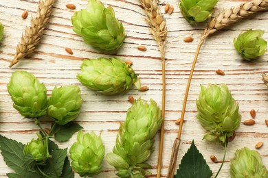 Flat lay composition with fresh green hops and wheat ears on white wooden table