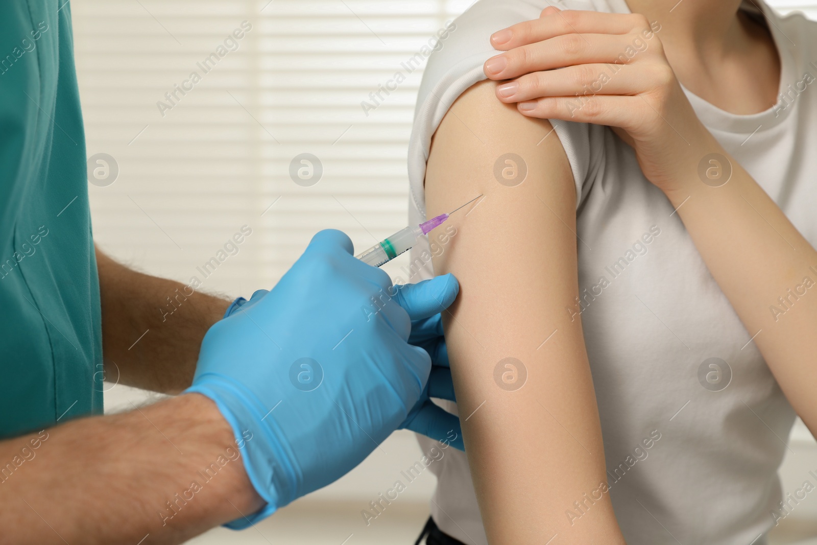 Photo of Doctor giving hepatitis vaccine to patient in clinic, closeup