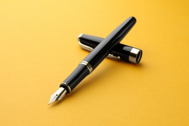 Stylish fountain pen with cap on yellow background