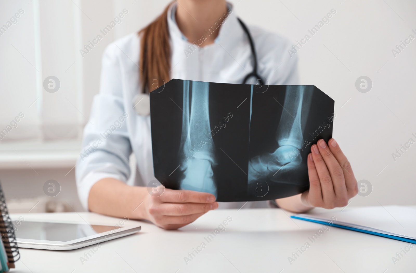 Photo of Orthopedist examining X-ray picture at desk in office, closeup