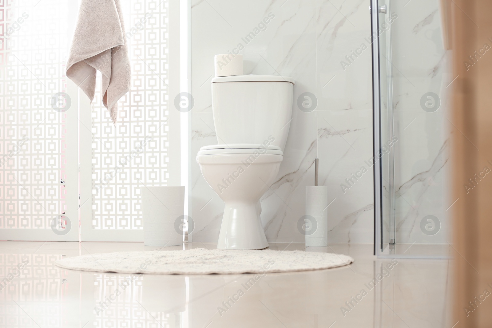 Photo of Modern toilet bowl with roll of paper in bathroom