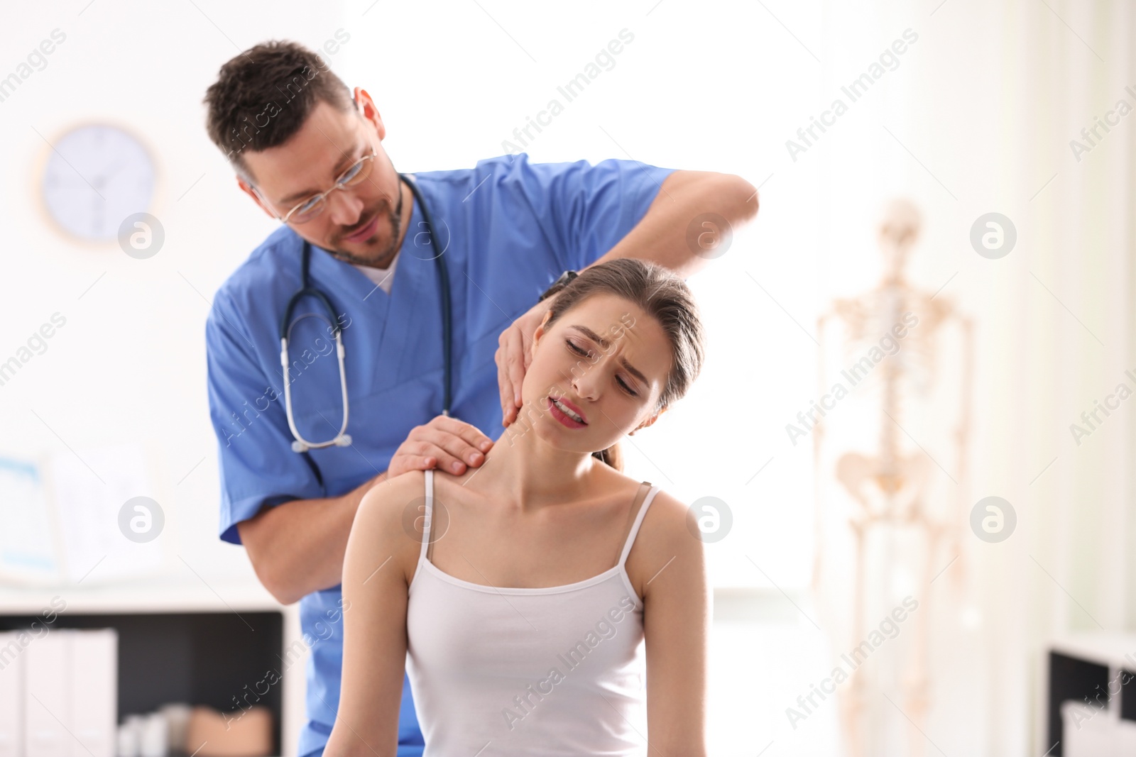 Photo of Male orthopedist examining patient's neck in clinic